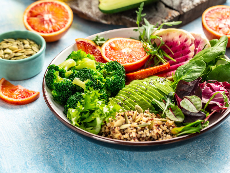 Quinoa bowl salad with vegetables, avocado, blood orange, broccoli, watermelon radish, spinach, pumpkin seeds. Food recipe background. Close up,