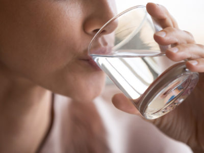 Close up woman drinking pure mineral water, holding glass,