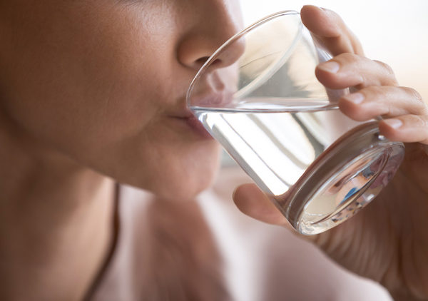 Close up woman drinking pure mineral water, holding glass,